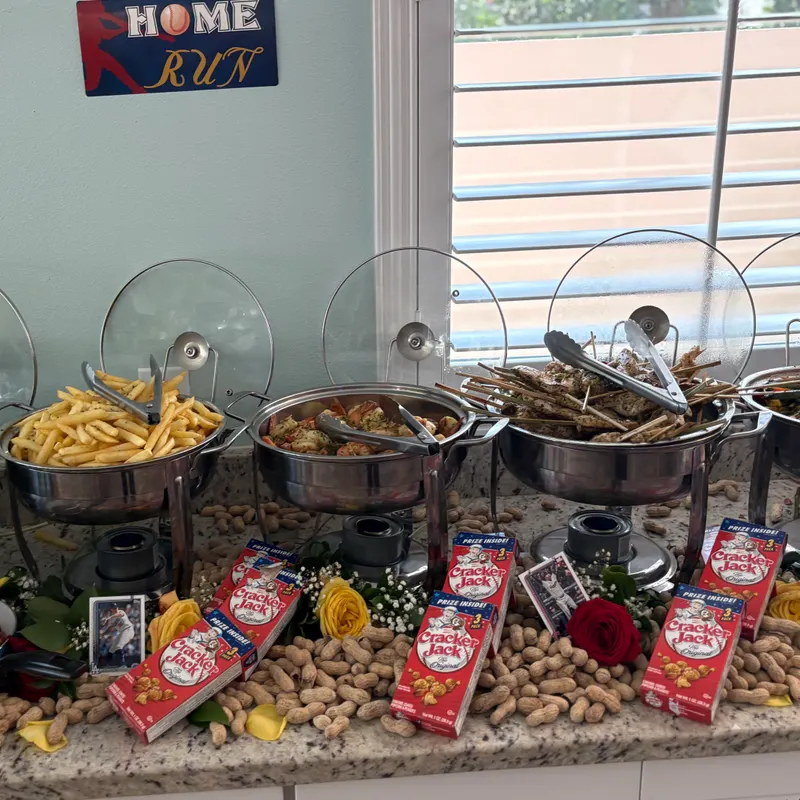 Baseball-themed party buffet with seafood boil, grilled skewers, crispy fries, and Cracker Jack decorations