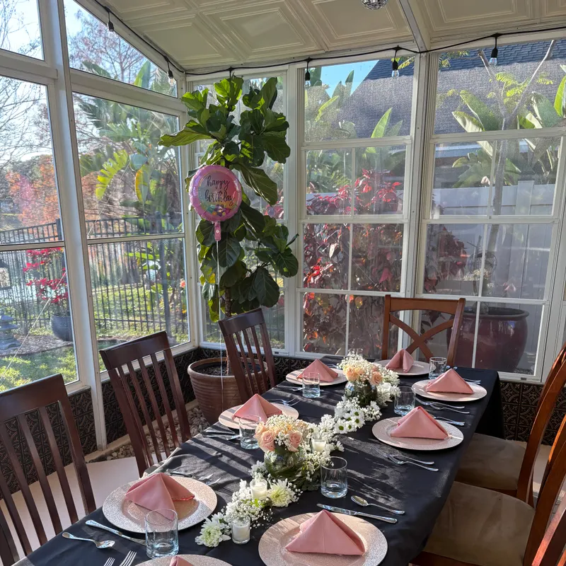 Birthday dinner table set with blush napkins, gold chargers, and fresh floral centerpieces in a Central Florida home