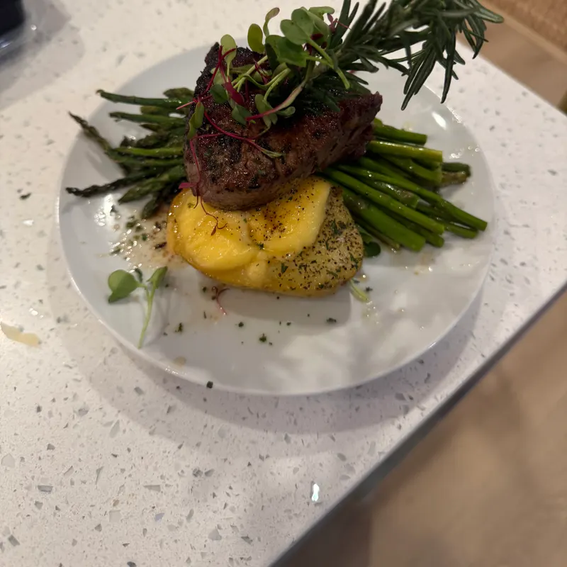 Plated filet mignon over gold potatoes with grilled asparagus, rosemary, and microgreens